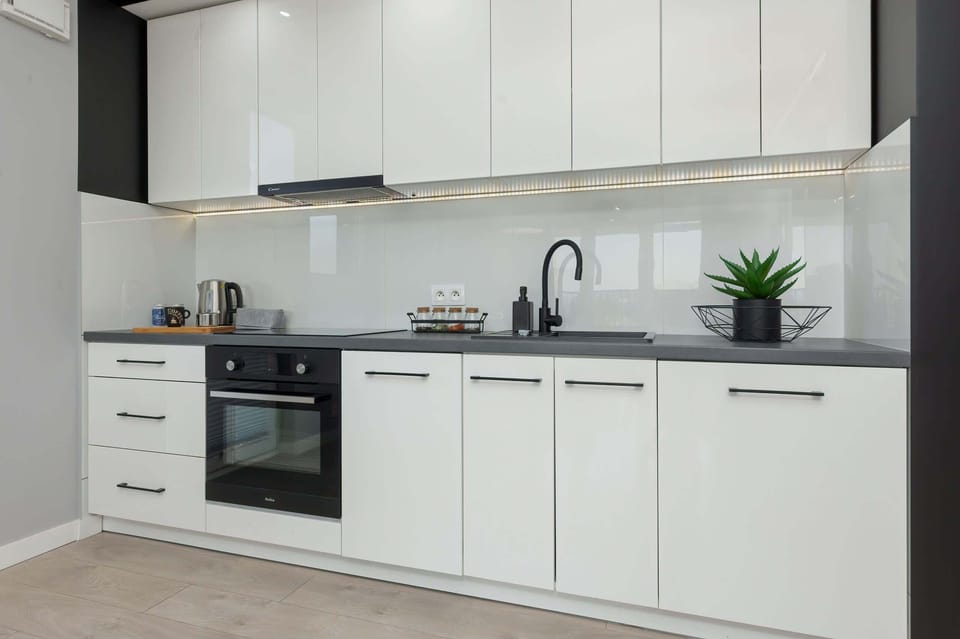 A kitchen with clean white finishes, a built-in oven, and modern appliances, designed for practicality and style.
