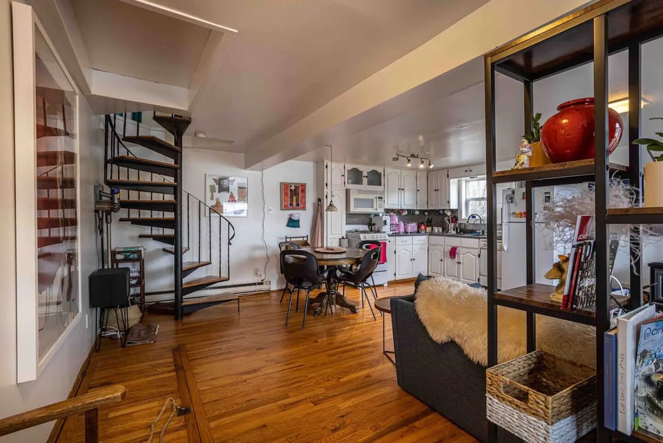 Step into a seamless blend of modern living in this snapshot, guiding you to the heart of the home – an expansive open-concept space, complete with a stylish kitchen and an eye-catching spiral staircase. 🏡✨ 