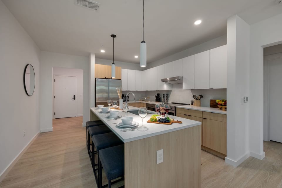 Fully equipped modern kitchen with basic cooking essentials, stainless steel appliances, island bar seating, Keurig coffee machine, and wet bar.