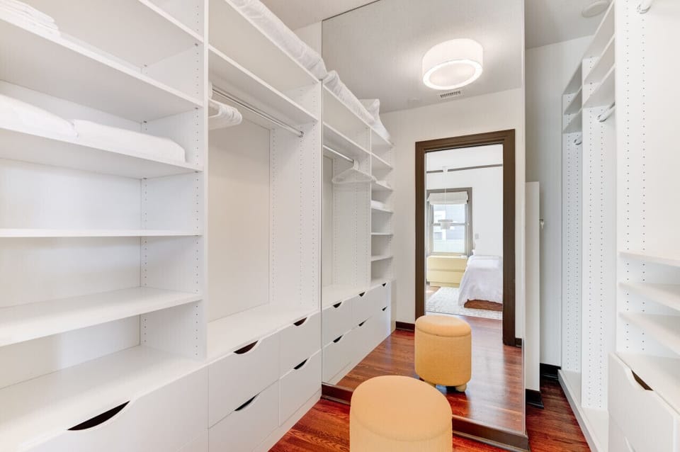 Ample storage awaits in this spacious walk-in closet w/ mirror/footstool.