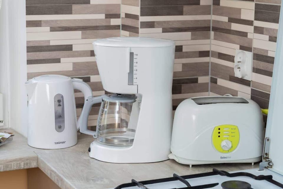 A close-up of kitchen appliances, including a coffee maker and toaster, on a modern countertop.







