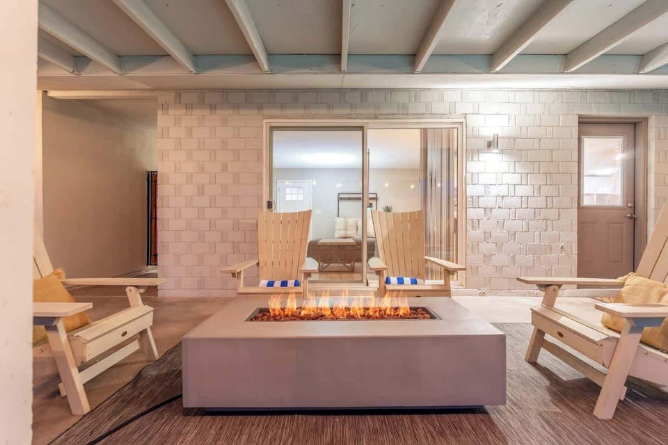 Gather around your private fire pit on this covered patio, where cozy seating and modern design invite you to unwind under the soft glow of evening light.