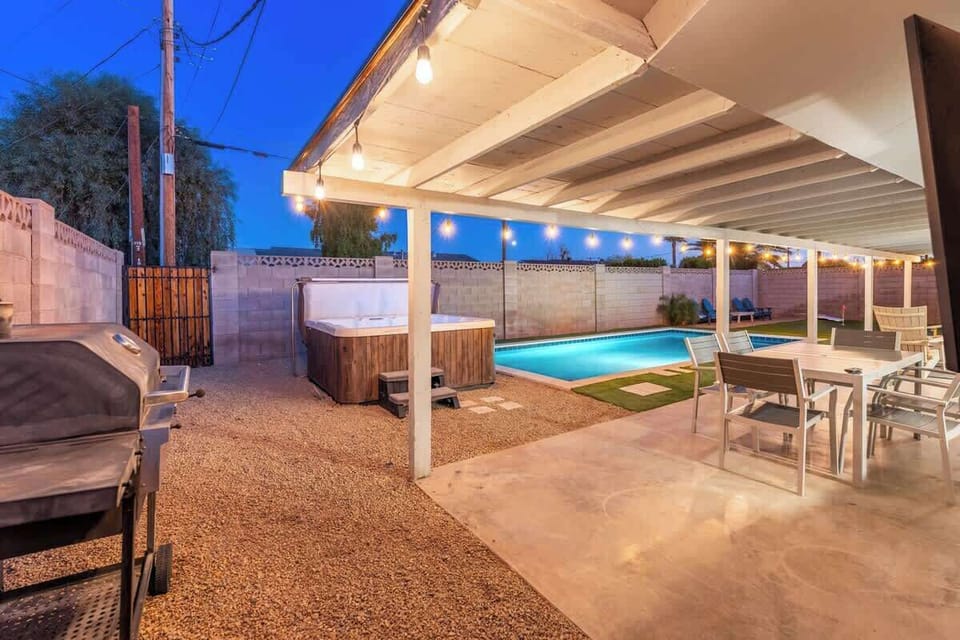 Your private backyard oasis awaits with a sparkling pool, bubbling hot tub, covered dining area, and BBQ grill—perfect for warm evenings under string lights with loved ones.