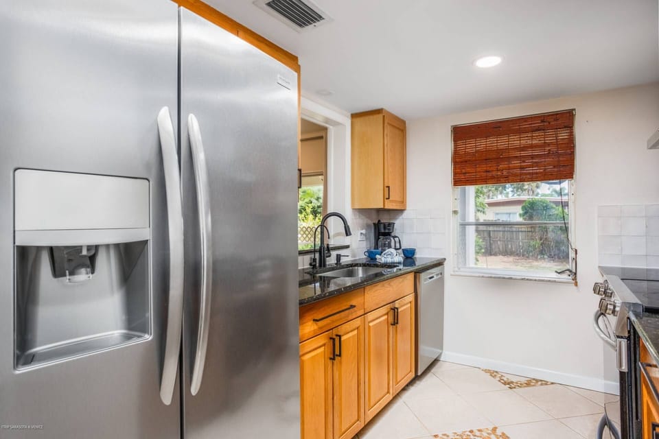 Alley kitchen with stainless appliances, granite counters and tile flooring.