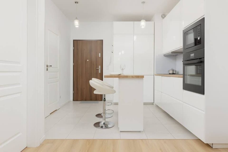 A modern kitchen corner featuring white cabinets, a built-in oven, and a wooden countertop, designed for functionality.
