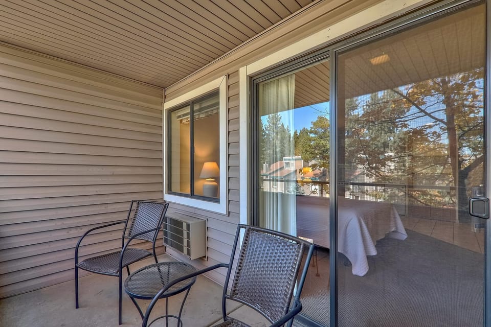 Relax on your private balcony with comfortable seating and peaceful neighborhood views through the trees.