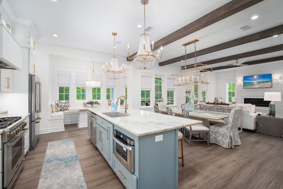 Your gourmet kitchen flows seamlessly into a light-filled dining and living space with elegant chandeliers and exposed beams creating the perfect gathering spot.