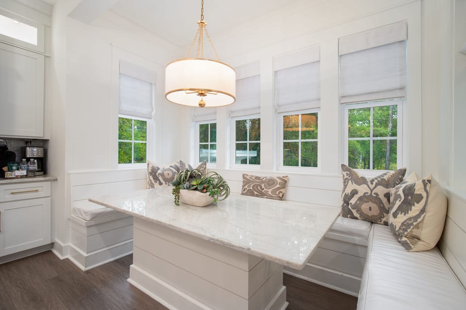 Your breakfast nook wraps you in bright elegance with built-in seating and stylish cushions beneath natural light.
