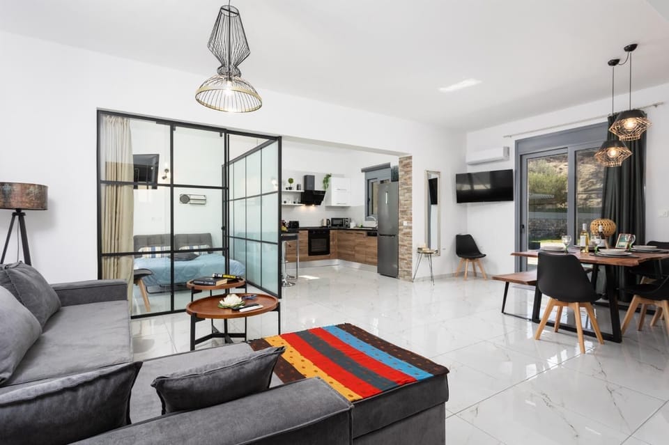 Open-plan living room with sofa, dining area, kitchen, A/C, WiFi internet, and satellite TV