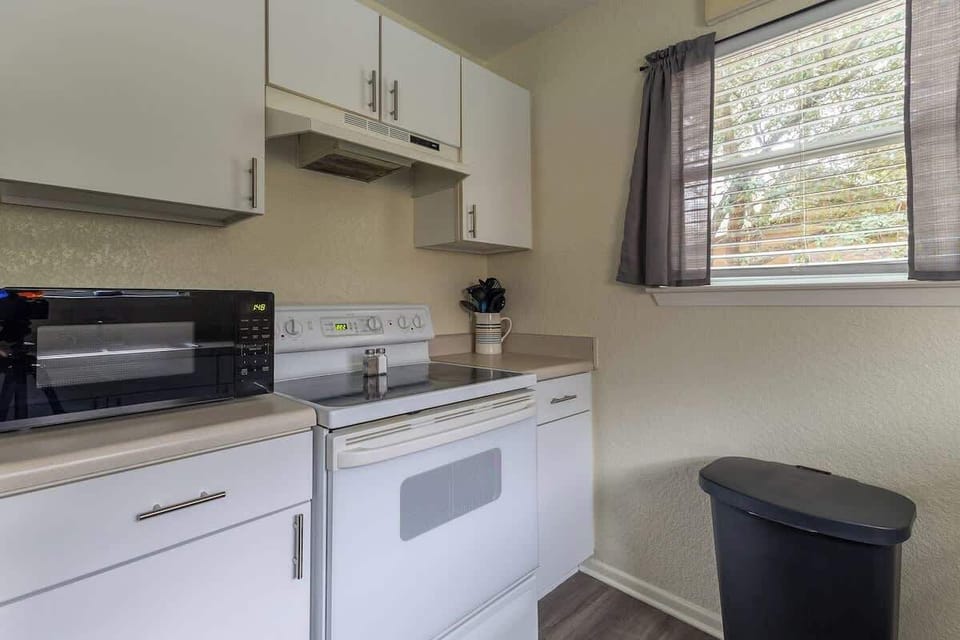 right and fully equipped kitchen with clean white cabinetry, full stove, microwave, and coffee station—perfect for preparing meals during your riverfront stay.
