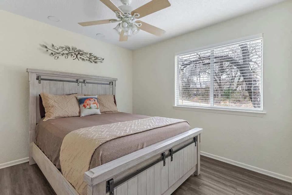 Bright room with Queen bed, ceiling fan, and large windows—perfect for kids, friends, or extra guests needing a comfortable restful space.