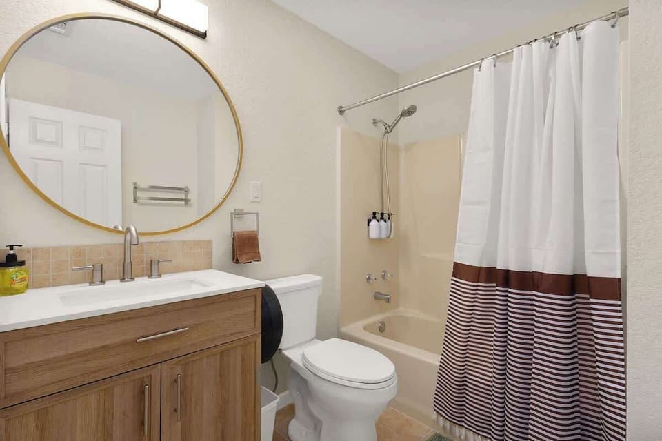 Clean bathroom with full tub/shower, bright lighting, and essential toiletries for a refreshing stay.