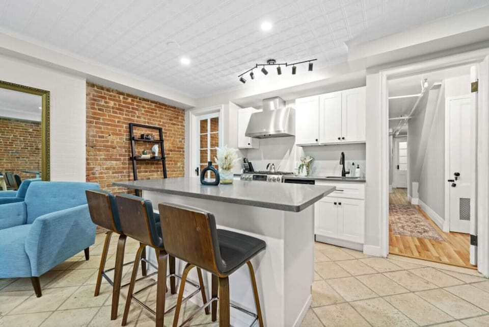 In this compact kitchen, a counter with three chairs offers a snug dining area. Complete with a stove and fridge, it caters to all your culinary requirements in this thoughtfully designed space.