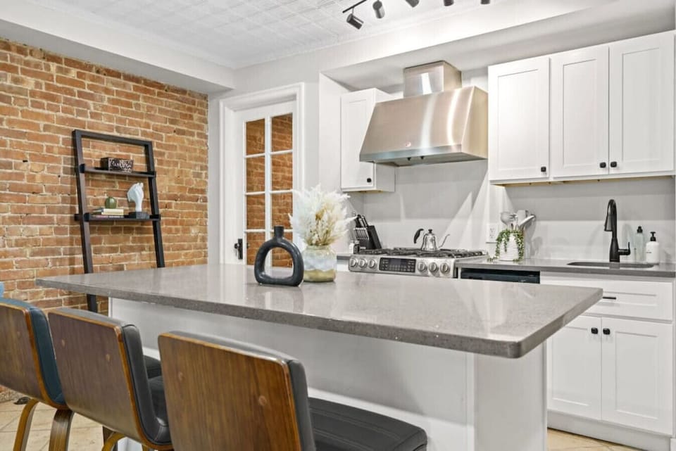 This newly renovated kitchen is fully equipped, featuring a central counter with three accompanying chairs.