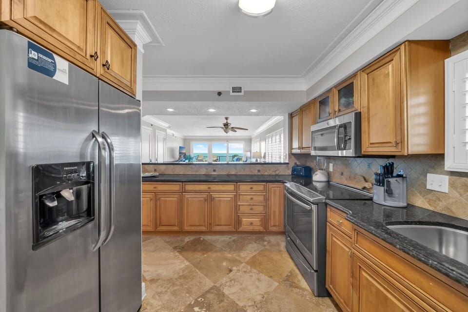 Your fully equipped kitchen features granite counters, stainless steel appliances, and warm wood cabinetry perfect for preparing meals.
