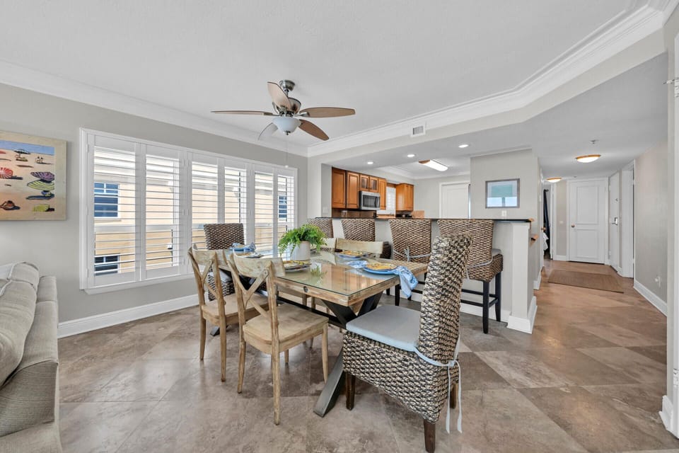 Gather around your elegant dining table where natural light streams through plantation shutters, creating the perfect setting for memorable meals together.