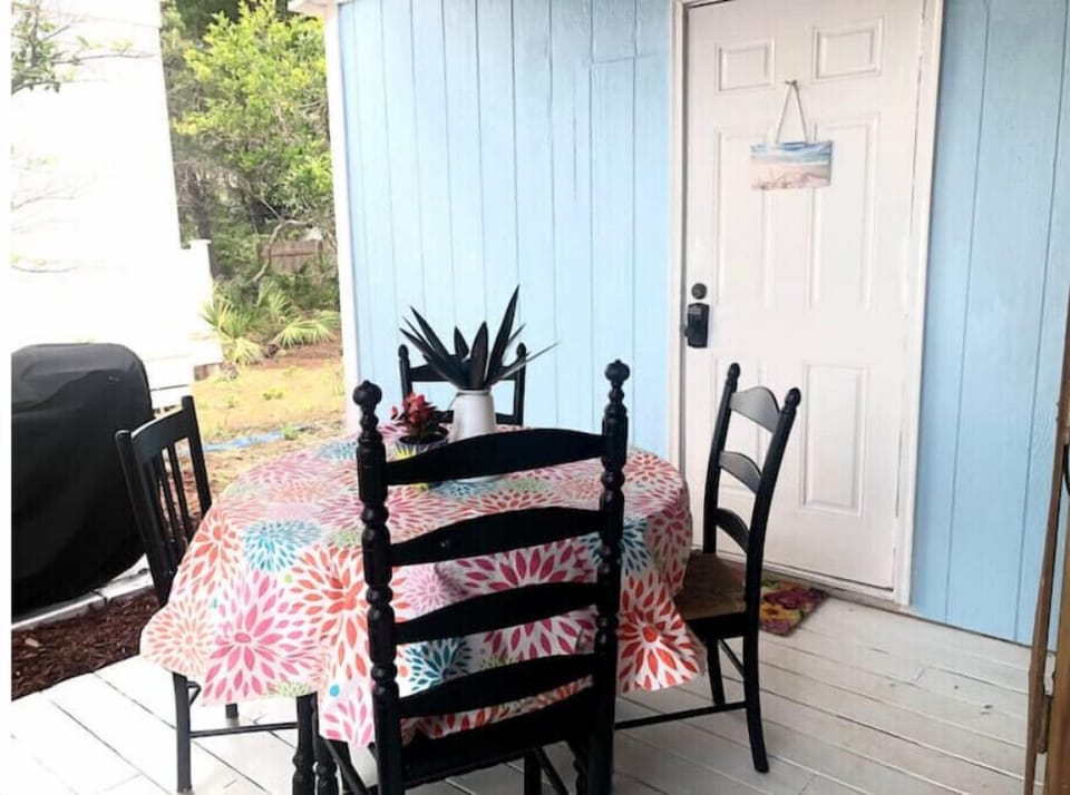 Bbq grill close to dining table beneath sheltered porch.