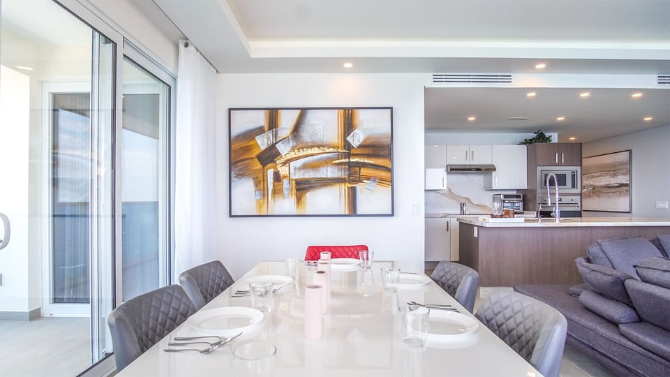 Six seat dining table hugs the floor to ceiling windows.