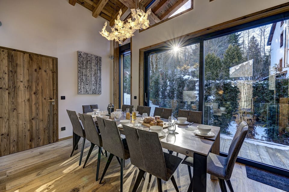 Dining table for 10 people beside glass doors onto balcony with BBQ