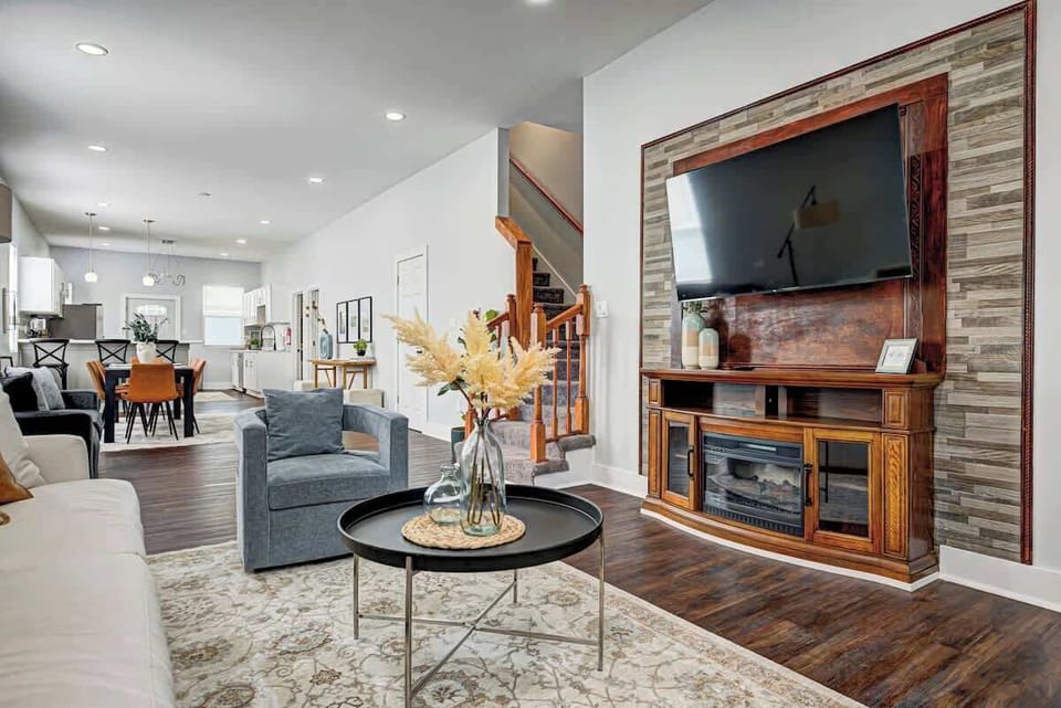 Cozy and inviting, this living room features a plush sofa and a comfy swivel chair, perfect for relaxation. Several poufs offer extra seating, while a large smart TV sets the scene for movie nights and entertaining!
