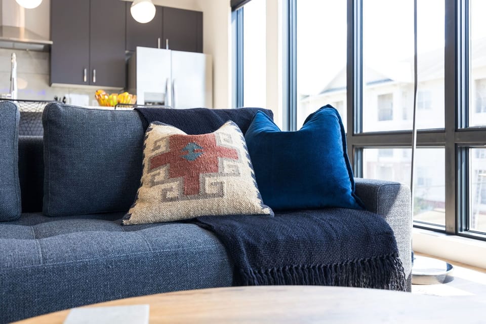 Bright open concept living area with floor to ceiling windows providing panoramic views of Midtown! Features designer furniture, smart TV, and access to private balcony.