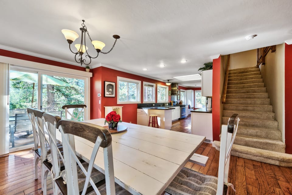 Gather around your spacious farmhouse dining table where warm red walls and natural light create the perfect setting for memorable meals together.