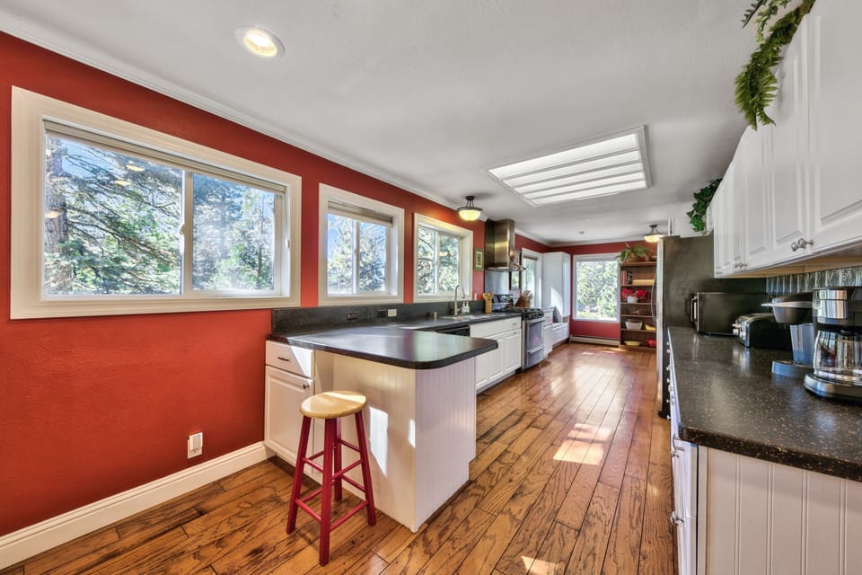 Your gourmet kitchen welcomes you with gleaming granite counters, rich hardwood floors, and charming red accent walls.