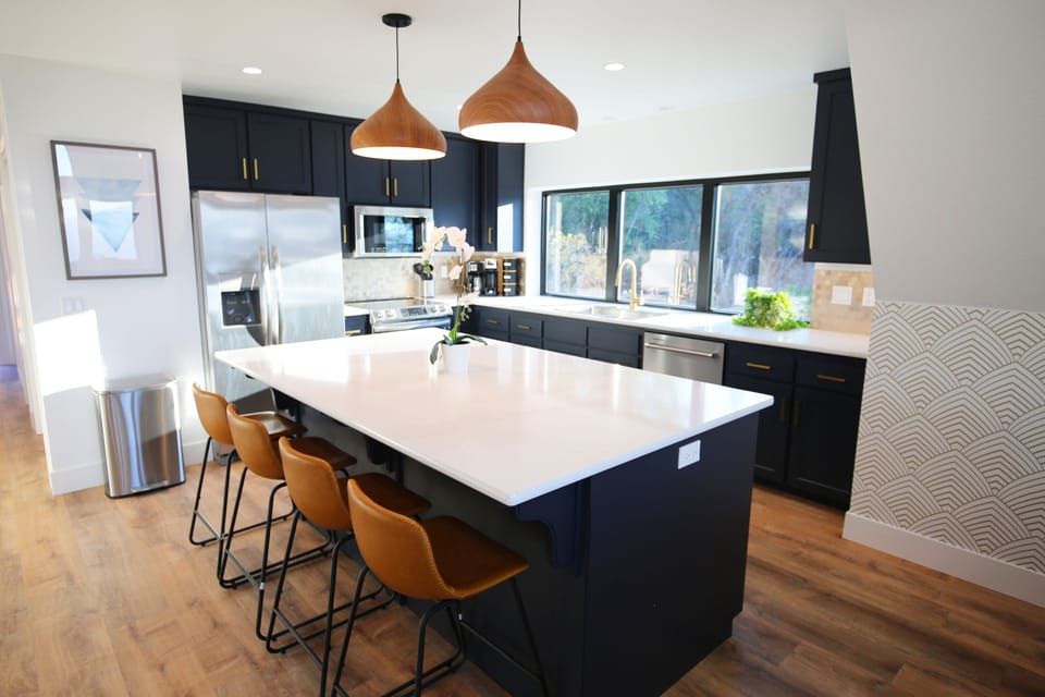Quartz countertops, gold backsplash and handles, with stainless appliances. 