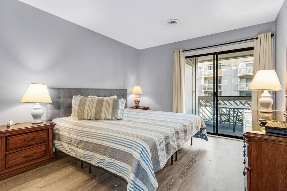 King bed, large dresser, closet, en suite bathroom and access to the balcony