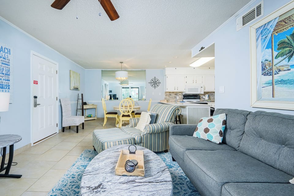 This inviting living area features a cozy gray sofa, a striped chair, and a vibrant blue rug, perfect for relaxation