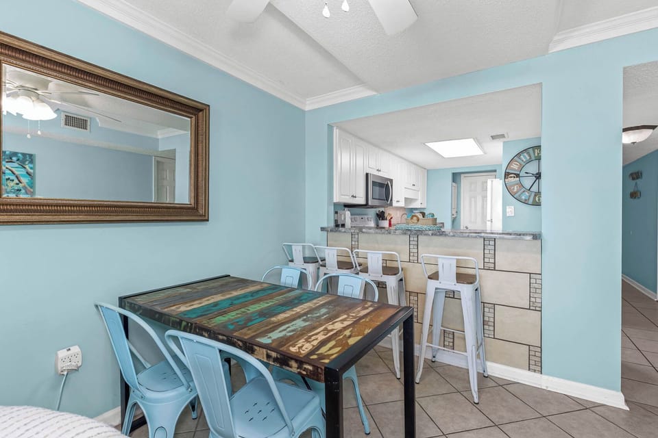 Inviting dining area featuring a rustic table and modern bar stools against a cheerful blue backdrop
