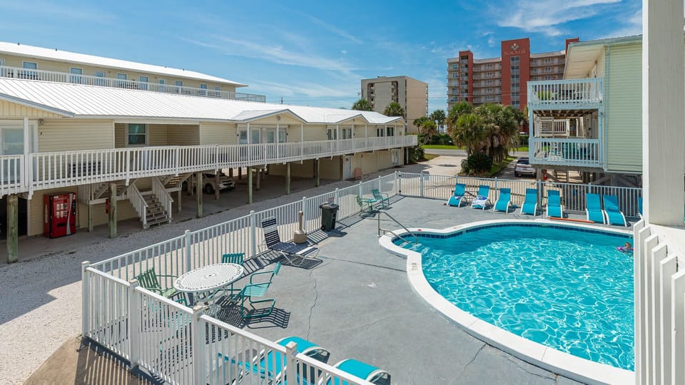 The inviting pool area features a sparkling blue pool surrounded by comfortable lounge chairs, perfect for relaxation and fun