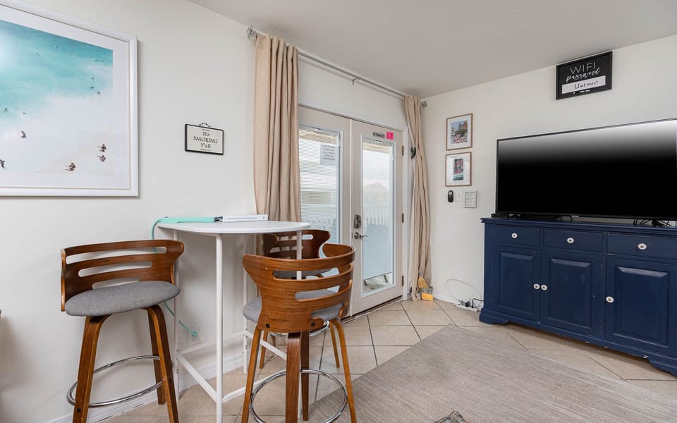 This cozy living area features a large TV, stylish bar stool seating area, and easy access to the outdoor space