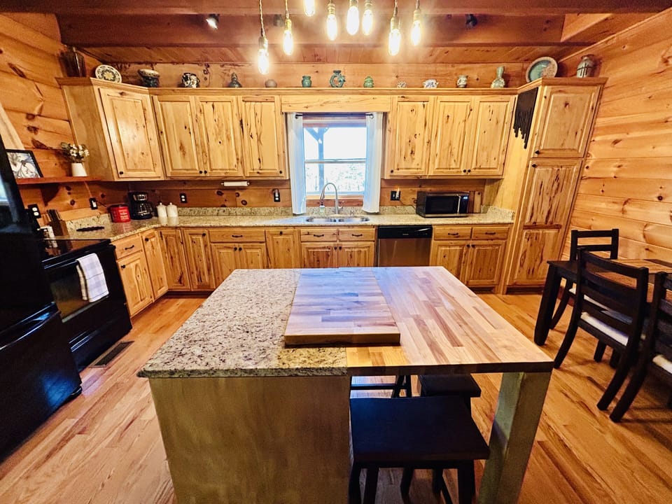 Kitchen features dimmable beam pendant lighting, dining area, and local art.