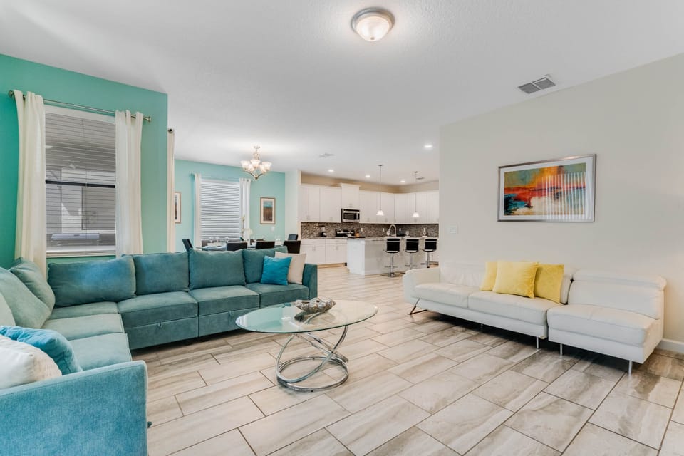 - Bright open-concept living room with modern design  
- Spacious sectional and glass coffee table for comfort  
- Easy flow to kitchen and dining ideal for group stays