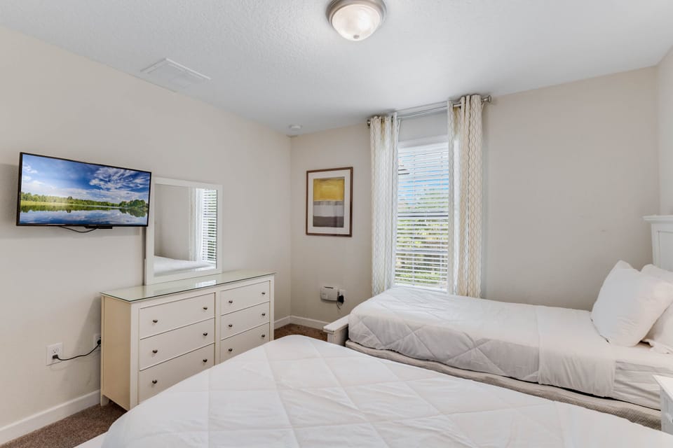 - Twin bedroom with two beds and natural light décor  
- Neutral tones, flat-screen TV, and dresser storage  
- Perfect for kids, teens, or extra guests in Orlando
