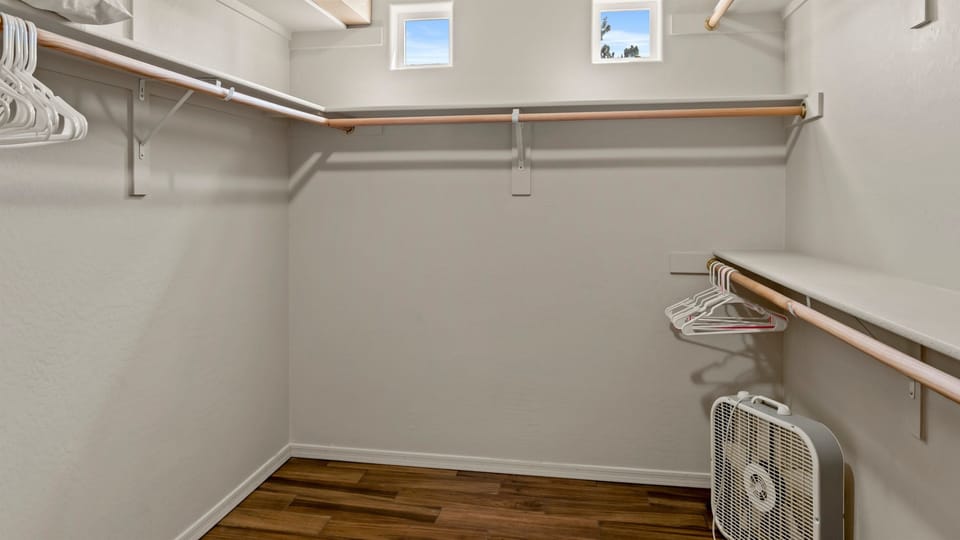 Explore the spacious walk-in closet, complete with hangers and extra storage, featuring a box fan for your convenience.