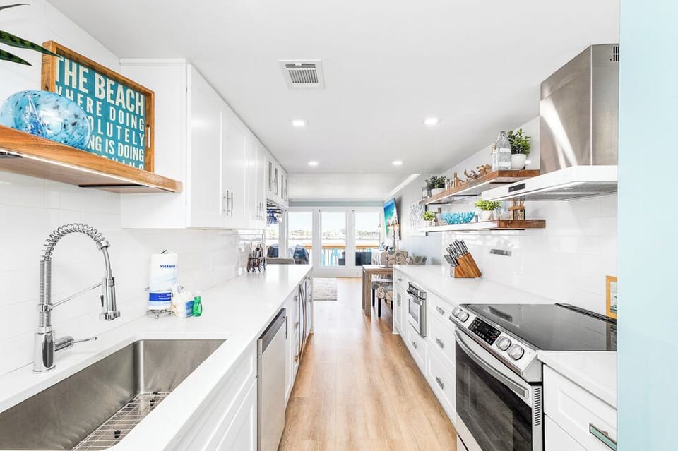 Your spacious galley kitchen features gleaming white cabinets, quartz counters, and stainless appliances—perfect for preparing meals with ocean views.