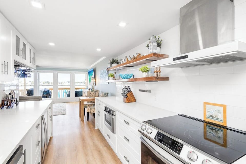 Your bright, modern kitchen invites culinary adventures with sleek white cabinetry, quality appliances, and gorgeous harbor views through expansive windows.