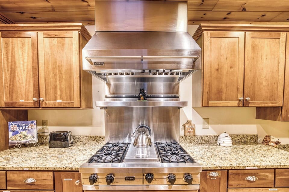 Cook like a pro in our spacious kitchen featuring a high-end Viking gas stove, commercial fan hood, and built-in food warmer. With ample counter space and storage, it's a chef's dream! 