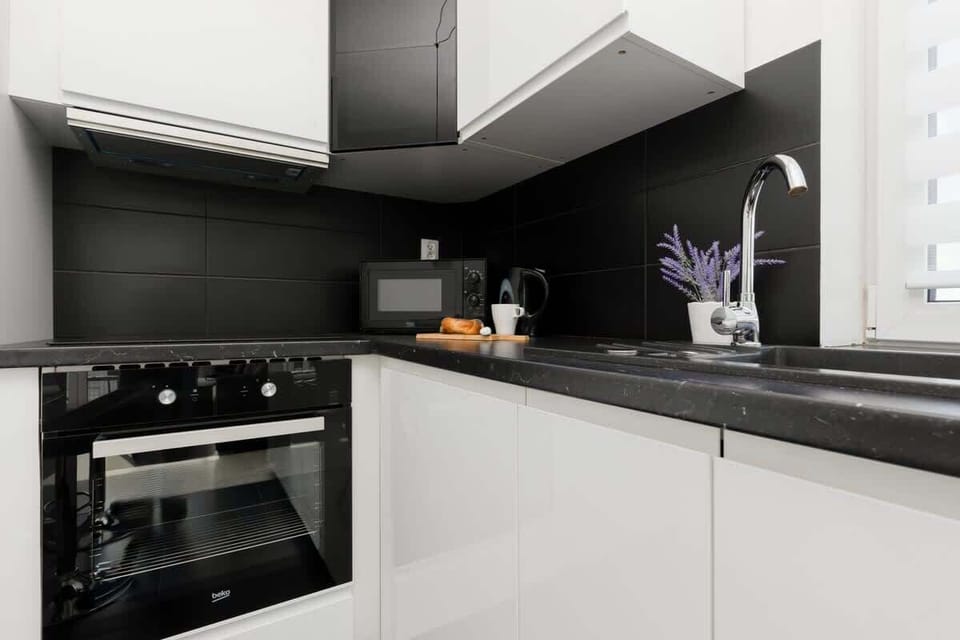 A fully equipped kitchen with modern appliances, a black and white color scheme, and clean, minimalist design.
