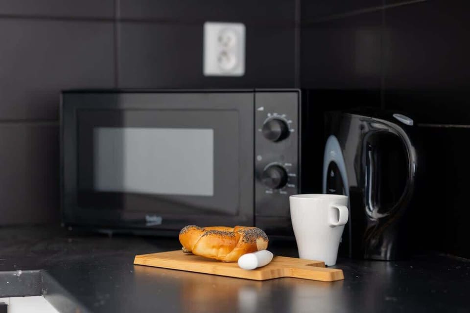 A detailed view of the kitchen counter, featuring a microwave, a kettle, and a small plate of pastries, creating a functional and inviting space.
