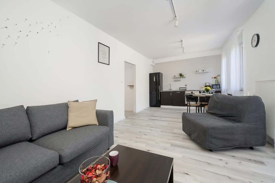 A different perspective of the living room, showcasing the grey sofa, a coffee table, and the light-filled space.

