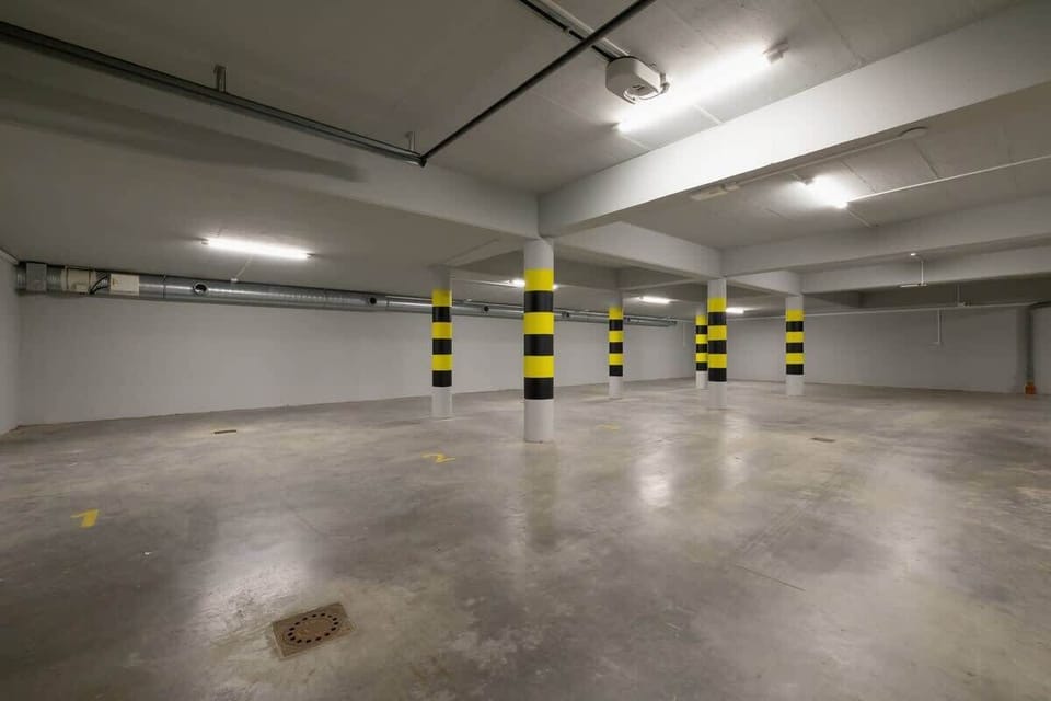 A spacious underground parking lot with visible safety markings and lighting.