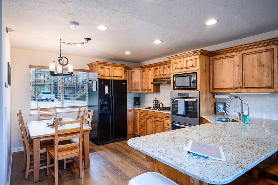 The gourmet kitchen features a breakfast bar with seating and is equipped with appliances, including a microwave, wall ovens, gas stove, and spacious refrigerator.