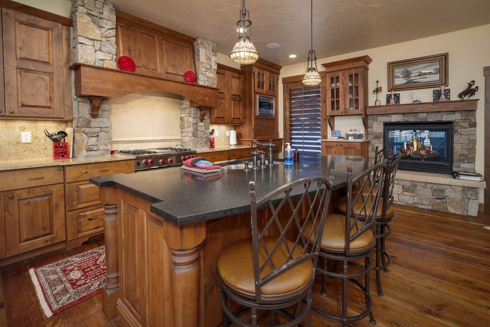 - Large kitchen island with cushioned stools is perfect for cooking and gathering - Stone arch and wooden cabinetry highlight rustic stylish craftsmanship - Warm tones and pendant lighting make this kitchen a hosting haven