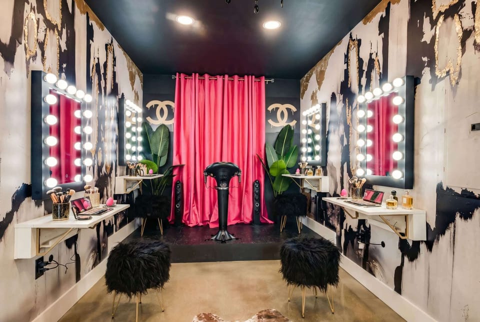 Hollywood vanity mirrors and red-curtained makeup stations turn this room into a full glam squad headquarters