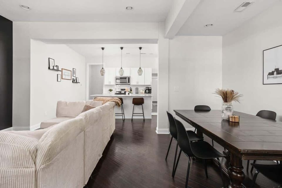 A view of the dining table, a sofa on the of the living area to the kitchen.