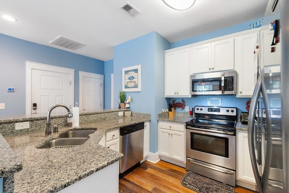 Your fully equipped kitchen features granite counters, stainless appliances, and soothing coastal blue walls for preparing memorable meals.
