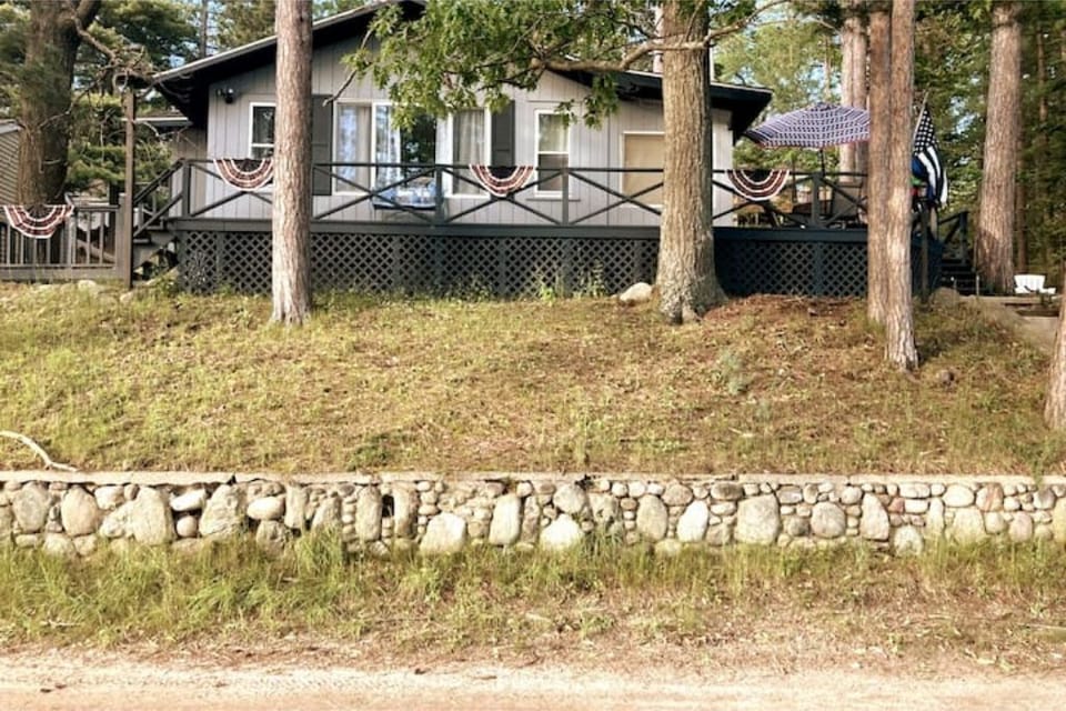 Front of house from parking spots located across dirt road at bottom of hill